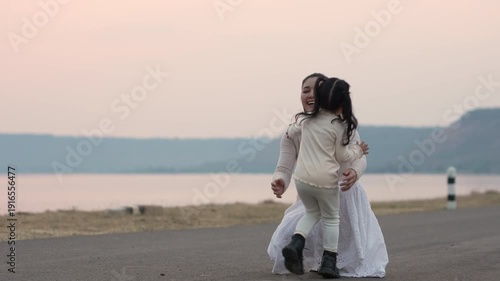 slow motion of Heartwarming moment of mother and child girl hugging by the lakeside at sunset
