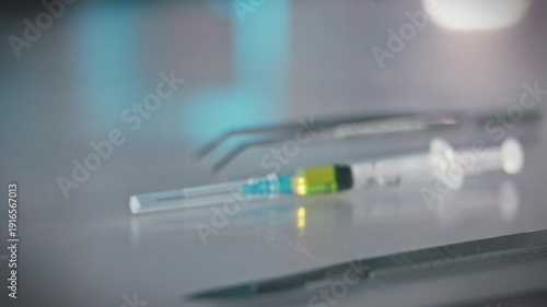 A medical professionals hands carefully grasp a prepared syringe containing medication amidst an array of surgical instruments, including a scalpel and tweezers, on a hospital operating room table