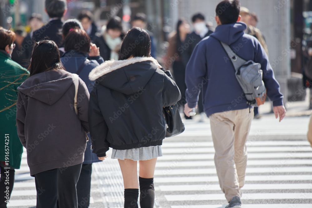 Obraz premium 冬の昼の名古屋の繁華街の横断歩道を渡る若い女性と人々の姿