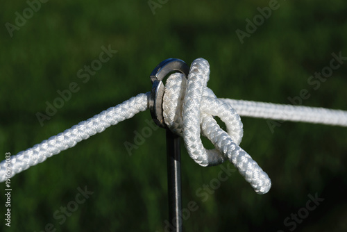 Macro of white rope knot secured to metal ring.