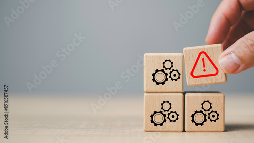 Wooden blocks with gear icons and red warning symbol, System failure, risk management, problem identification, and business process troubleshooting solutions.