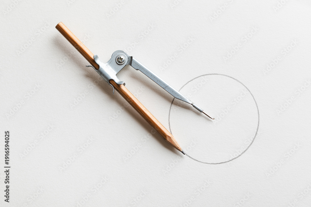 Fototapeta premium Drafting compass drawing circle on white paper background top view.