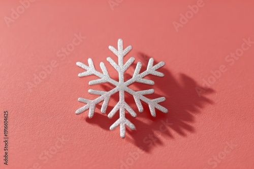 Delicate snowflake design casts soft shadow on vibrant coral bac
