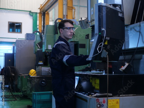 Factory engineer inspecting machining process on CNC machine in automotive manufacturing plant