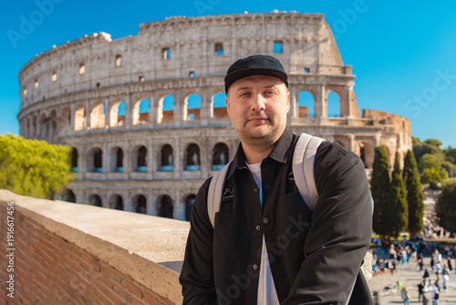 Handsome 30s tourist visiting Colosseum in Rome, Italy. Young man taking photo in front of famous Italian landmark. Travel and holidays concept. High quality photo