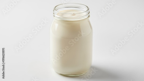 A glass jar filled with creamy white milk isolated on a light background