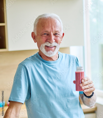 Wallpaper Mural A senior man is eating healhty fruit breakfast and drinking juice and water in kitchen. Having a break after a morning exercise. The man is enjoying his meal, vitality, healthy eating and active senio Torontodigital.ca