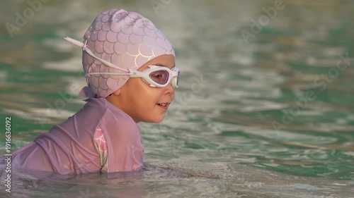 slow motion of happy preschool child girl playing and swimming in the pool