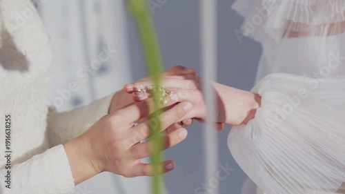 A beautiful bridal couple holds hands in nature as the bride carries a stunning flower bouquet, celebrating their love and marriage in a lush green spring setting