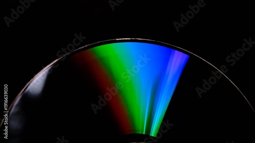 Abstract concept, The CD DVD spins gleaming colorful rainbow on a black background 