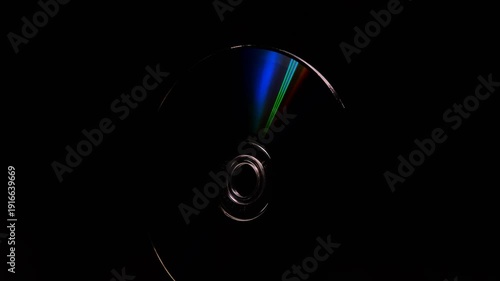 Abstract concept, The CD DVD spins gleaming colorful rainbow on a black background 