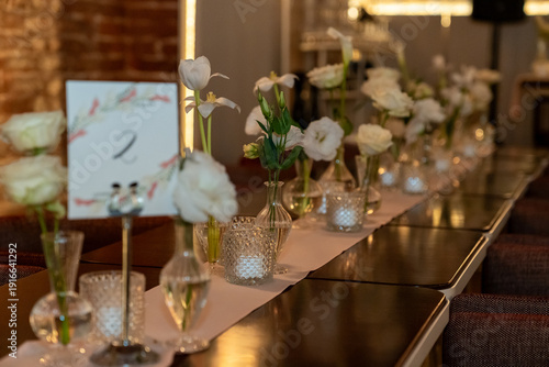 Close up view of wedding table setting with flowers and candles in a warm scene.