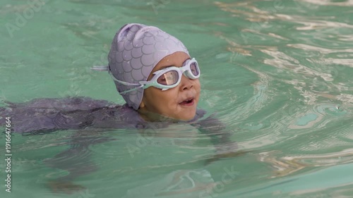 slow motion of preschool child girl playing and swimming in the pool