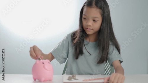 collections video Asian kid girl count and putting coin into pink piggy bank. Concept of financial literacy for kids, saving money for future education, investment planning, Isolated light background.