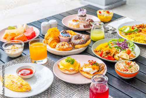 Delicious breakfast buffet with eggs benedict, fresh fruit, pastries, and juice on outdoor table, ideal for vibrant dining, brunch, or lifestyle themes.