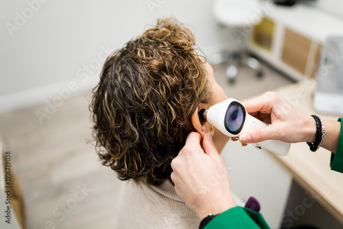 An unrecognizable 60-year-old woman undergoes hearing tests at a medical center. The woman is having her ears examined with a video otoscope. Concept of an otolaryngologist