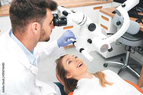 Dentist checking up patient teeth with microscope
