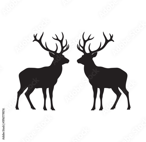 Two deer with large antlers facing each other in profile view standing side by side