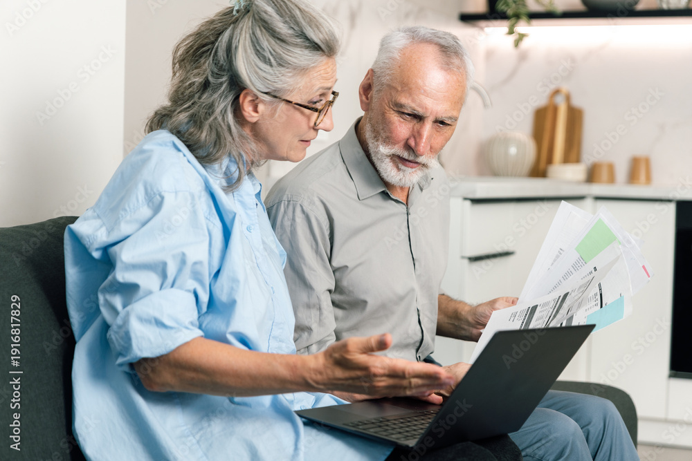 Fototapeta premium Couple discusses bills and budget while reviewing statements on laptop at home