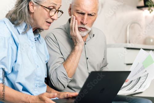 Foto Elderly couple reviews online bank statements on a laptop at home