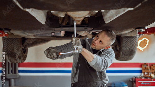 фотографія Auto Mechanic Working Under Car in Garage Performing Vehicle Repair and Maintena