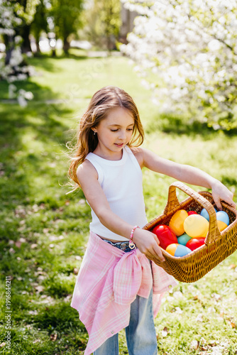 Portrait of happy child holding Easter basket on easter egg hunt. Joyful outdoor family moment celebrating Easter, childhood, and seasonal traditions.