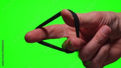 A close-up of a woman's hair tie in a person's hand against a green isolated background.
Elastic hair tie in hand