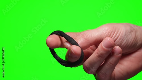 A close-up of a woman's hair tie in a person's hand against a green isolated background.
Elastic hair tie in hand