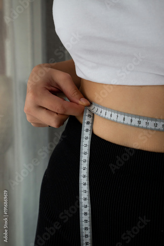 Canvas Print Woman measuring waist with tape measure to track fitness progress, weight loss, health, and body goals for monitoring weight loss and well-being