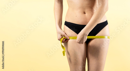 Woman measuring thigh with tape for weight loss progress