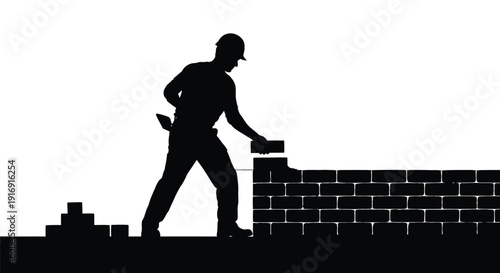 Silhouette of construction worker wearing hard hat carefully laying bricks to build a solid structure