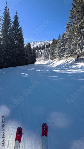 Beautiful POV ski landscape on the mountains. Skier skis down a snowy mountain trail in sunny weather.