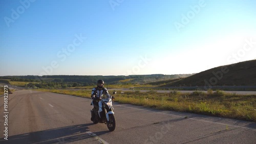 Man riding on a motorbike. Motorcyclist driving his motorcycle on country road during sunset. Slow motion Side view Close up