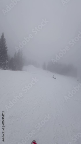 Concept of bad weather and snow storm. A skier skis down a snowy slope in poor weather and visibility. First-person view. Vertical shot
