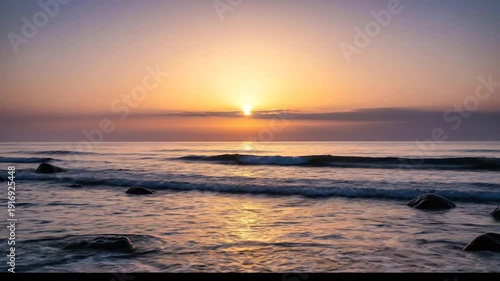 Serene Ocean Sunrise with Gentle Waves and Rocky Shoreline.