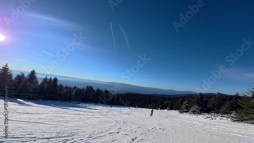 Beautiful POV ski landscape on the mountains. Skier skis down a snowy mountain trail in sunny weather.