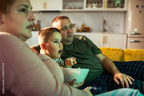 Bild auf Leinwand Family watching tv with popcorn on the sofa at home