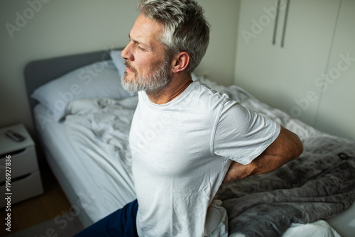 Photos Mature man with back pain sitting on bed at home