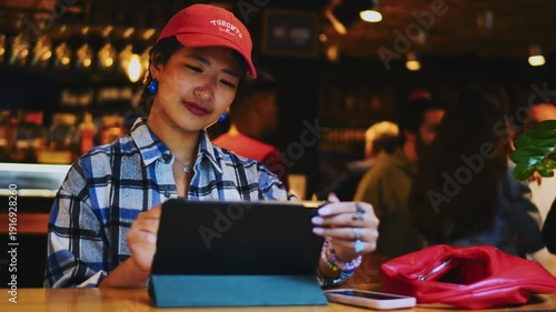 Professional male expert using digital tablet with stylus sitting in outdoor restaurant, ambitious businessman working on project during lunch, authentic representation of startup culture