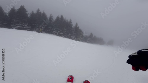 Concept of bad weather and snow storm. A skier skis down a snowy slope in poor weather and visibility. First-person view