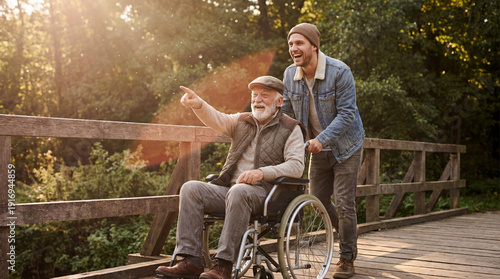 happy caucasian son pushing disabled senior father in wheelchair on bridge. elderly man pointing finger. caregiving and family lifestyle. healthcare, social assistance. banner, website header.