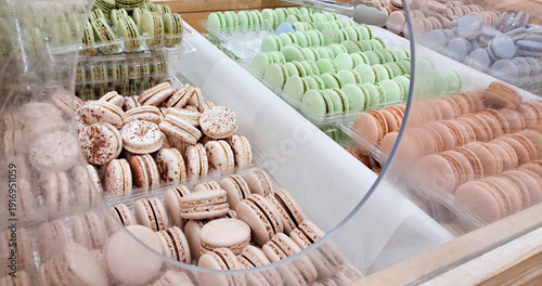 Assorted colorful macarons displayed for sale in a supermarket confectionery department showcase.