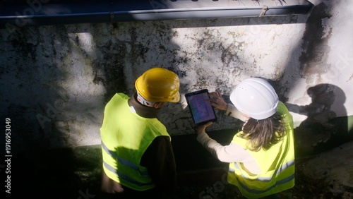 Fotografi Construction engineers working as a team, using a digital tablet to record data