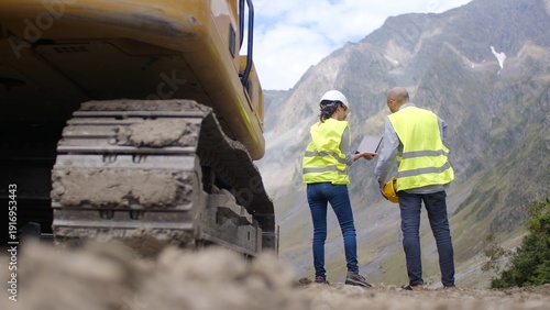 Obraz na plátně Construction engineers and workers collaborating on a project site, overlooking