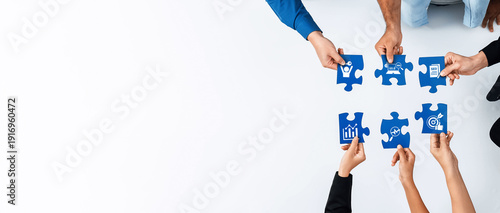 Obraz na płótnie Overhead view of diverse hands assembling blue puzzle pieces symbolizing business concepts such as growth, collaboration, and strategy in a creative workspace