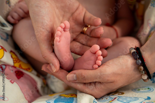 Tableau sur toile Close-up of a newborn baby’s feet held in adult hands