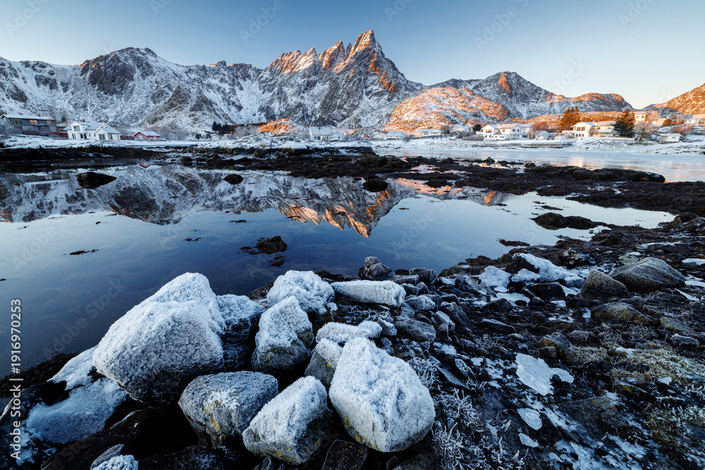 Obraz premium Snow covered rocks and mountain reflection in Arctic fjord at sunrise