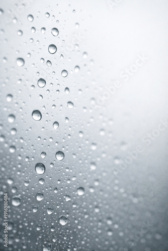 Extreme close-up of raindrops on glass with a softly blurred background, ideal as a calm weather texture and design backdrop.
