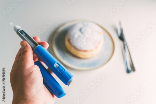Fotografie Medical injection pen like ozempic for weight loss or diabetes treatment with a blurred sugary donut in the background