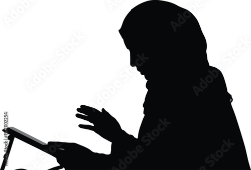 Silhouette of woman in hijab using a tablet computer